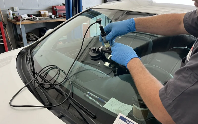 Technician injecting resin into a small rock chip with a bridge tool
